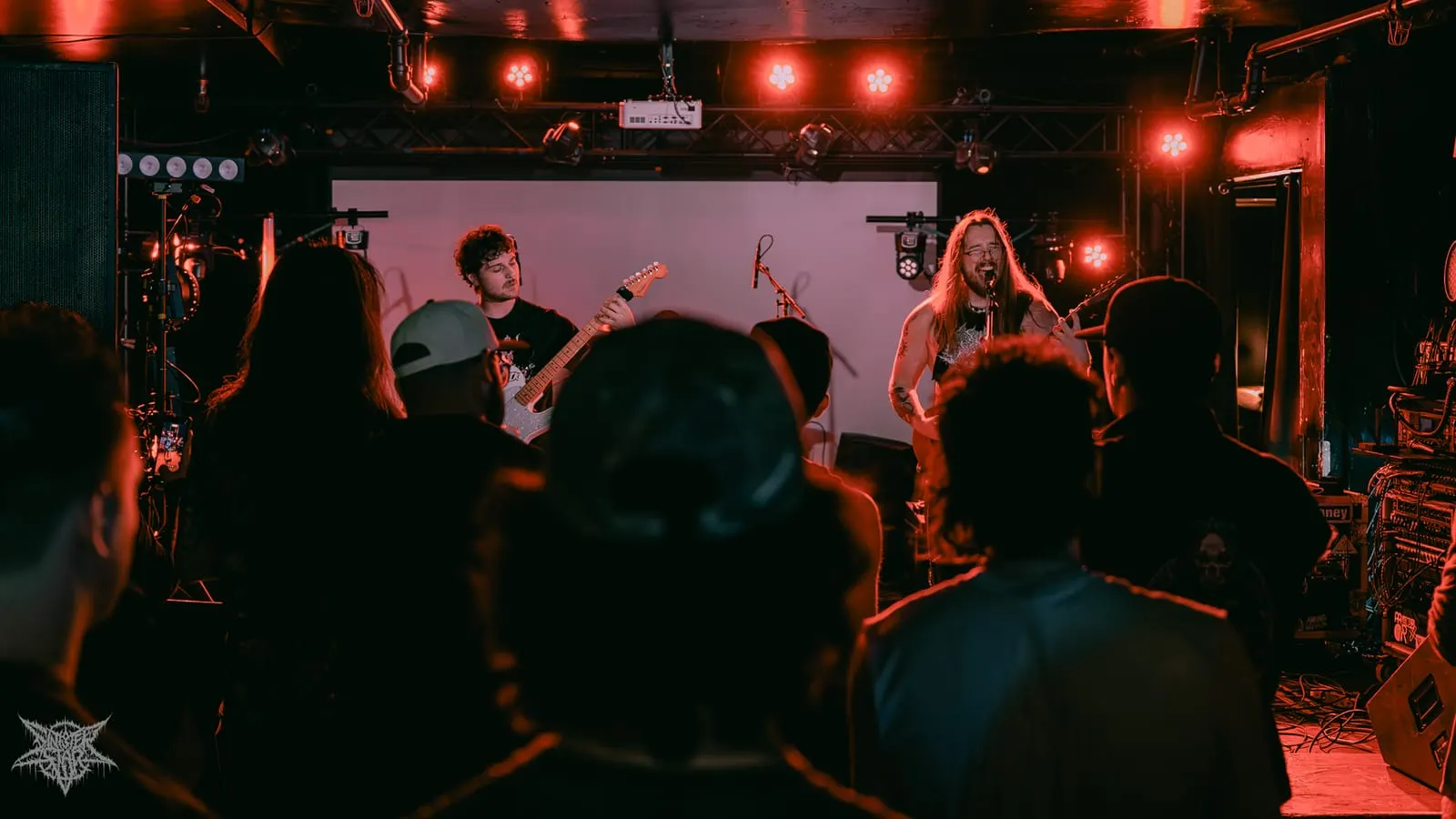 Bardo playing to a full room under red light, July 2026