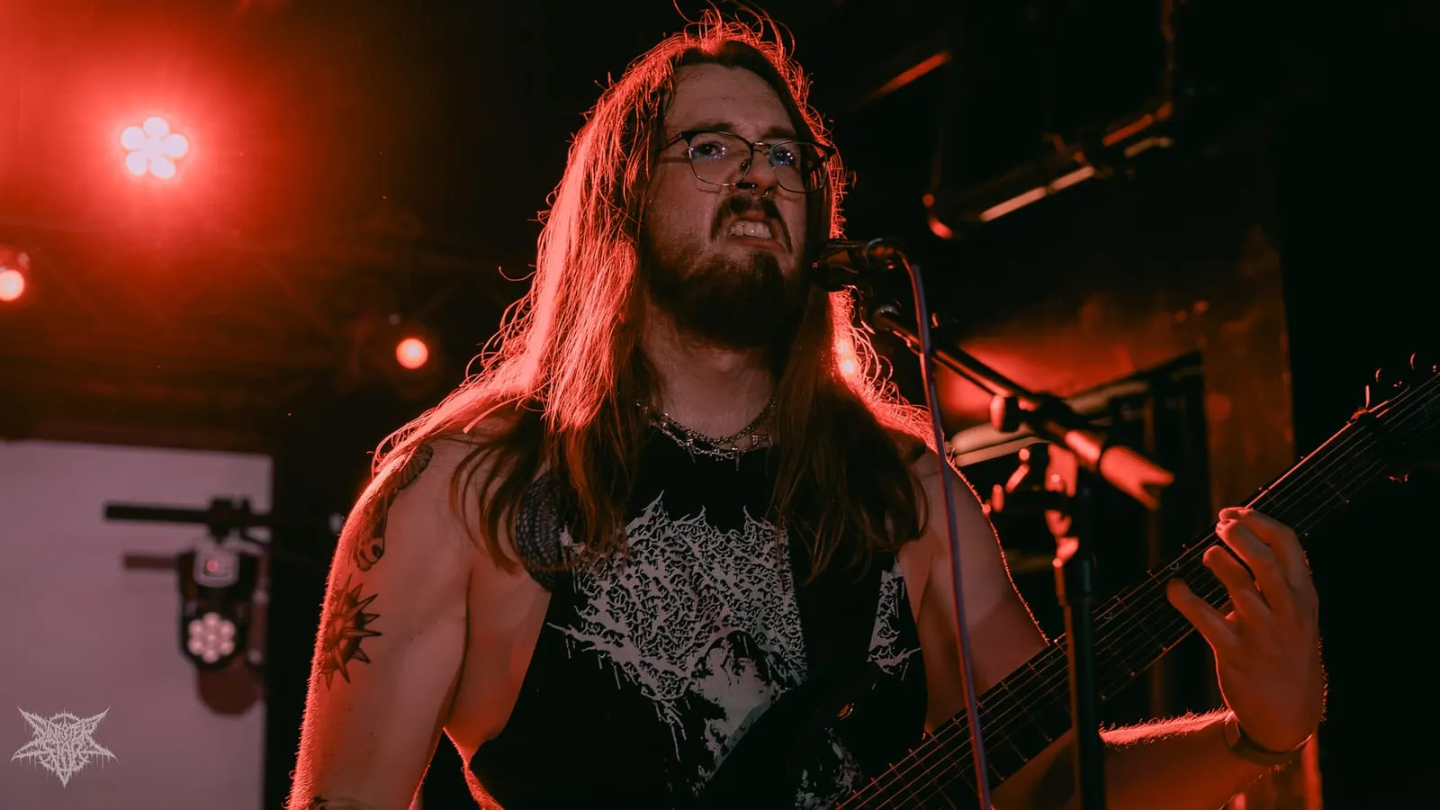 Vocalist at the mic under red light, July 2026
