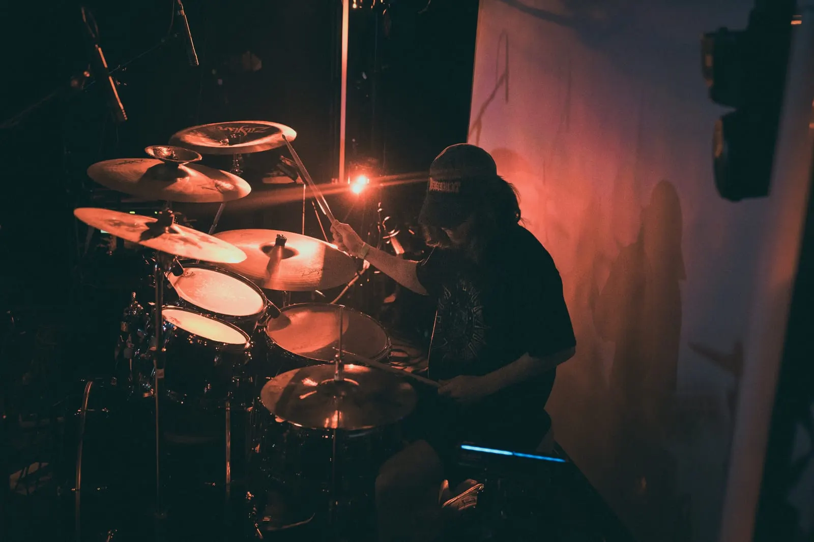 Drummer behind the kit under red light, July 2026